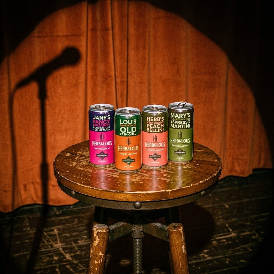 Herb & Lou's four cans, Jane, Lou, Herb and Mary, on a stool on a comedy stage